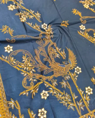 Kain batik sarung wanita motif Burung Paksi Sogan yang anggun di atas dasar kain hitam klasik, dengan seorang pembatik di latar belakang.
