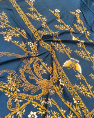 Kain batik sarung wanita motif Paksi dan Kupu Sogan di atas kain hitam klasik, dengan seorang pembatik di latar.