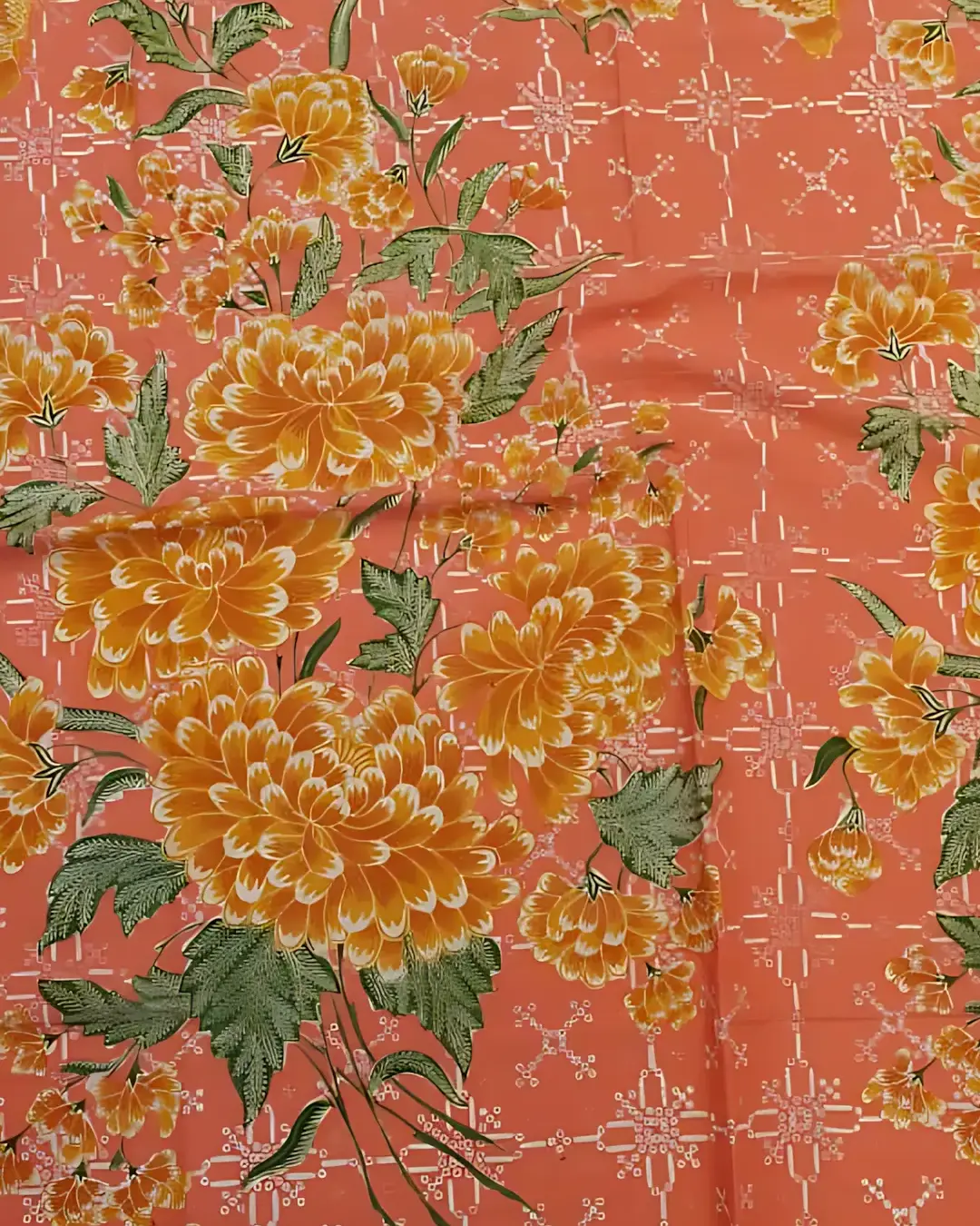 Sarung batik tulis katun primissima dengan motif bunga mekar berwarna kuning keemasan di atas dasar kain jingga yang hangat.